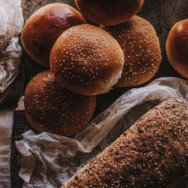 Artisan bread including loaves and buns, made with a 65-year-old starter, slow fermentation, and heritage grains.