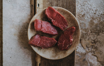 A plate of raw, grass fed lamb steaks.